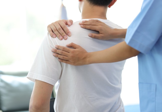 肩をおさえる男性とスタッフ
